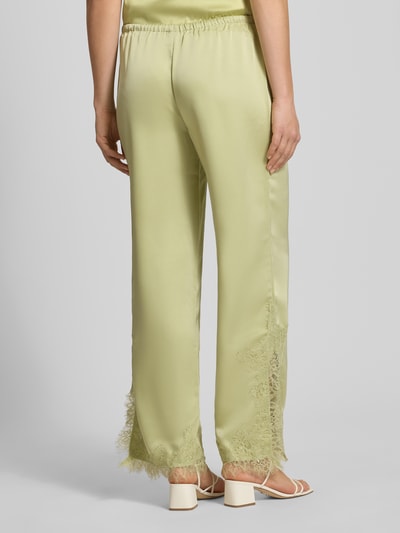 Frauenmodel trägt Flared Fit Stoffhose mit Spitzenbesatz von Gina Tricot aus Satin in Pastellgrün mit elastischem Bund und Tunnelzug, Ganzkörperansicht Rückansicht.