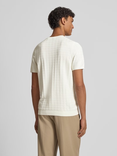 Männermodel trägt T-Shirt mit Label-Detail Modell 'Theor' von JOOP! Collection in Creme, feine Struktur, gerader Schnitt, Ganzkörperansicht Rückansicht.