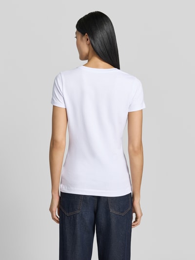 Frauenmodel trägt T-Shirt mit Logo und Rundhalsausschnitt von Guess im Slim Fit aus Baumwoll-Elasthan-Mix in Weiß, Ganzkörperansicht Rückansicht.