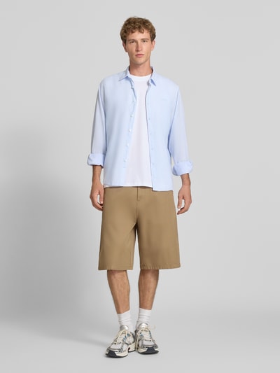 Męski model nosi Regular Fit Freizeithemd aus Leinen-Baumwoll-Mix Modell 'PAYTON' von Pepe Jeans, jasnoniebieski, jednokolorowy, kołnierzyk typu kent, listwa guzikowa na całej długości, wyhaftowane logo, długi rękaw z mankietem, materiał: mieszanka lnu i bawełny, wykończenie cieniowaną przędzą, pas na plecach z kontrafałdą, widok całej sylwetki z przodu.