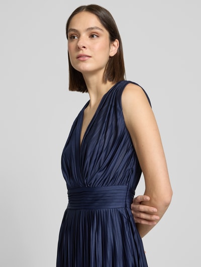 Frauenmodel trägt knielanges Cocktailkleid in Falten-Optik Modell 'Linn' von GUIDO MARIA KRETSCHMER WOMAN aus dunkelblauem Satin, Nahaufnahme Oberkörper.