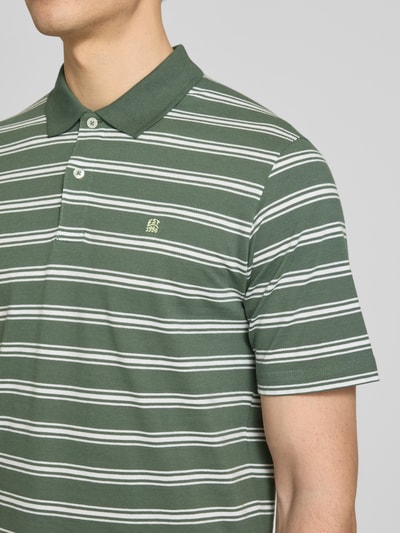 Männermodel trägt Regular Fit Poloshirt mit Logo-Stitching Modell 'Adam' von Jack & Jones Premium, grün mit weißen Streifen, reine Baumwolle, kurzärmeliges Design, Nahaufnahme Oberkörper.
