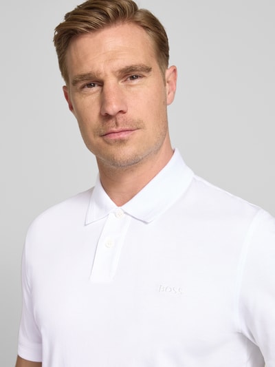 Męski model nosi Regular Fit Poloshirt aus reiner Baumwolle Modell 'INTERLOCK' von BOSS Orange, efekt: jednolity kolor, krój regular fit, aplikacja: wyhaftowane logo, kołnierzyk polo, zapięcie na 2 guziki, krótki rękaw, wykończenie materiału: dżersej, materiał: bawełna; zbliżenie na górną część ciała