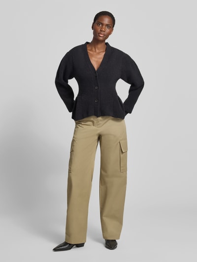 Frauenmodel trägt Relaxed Fit Cardigan aus Alpaka-Mix von ROTATE in Schwarz mit Strick-Optik, Volant-Saum und Knopfleiste, Ganzkörperansicht von vorne. Rückenlänge bei Größe S: 56 cm, elastischer Alpaka-Mix mit Woll-Anteil.
