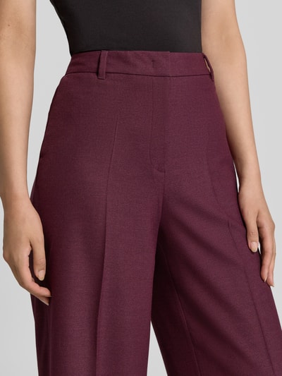 Frauenmodel trägt Wide Fit Hose mit Viskose-Anteil von Christian Berg Woman Selection, weinrote Farbe, Bundfalten, Nahaufnahme Oberkörper.