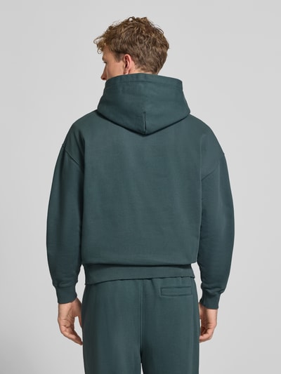 Männermodel trägt Oversized Fit Hoodie aus mieszanka bawełny Modell 'CLARITA' von PEGADOR, detal z logo, kieszeń kangurka, wykończenia elastyczne, Ganzkörperansicht Rückansicht