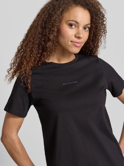 Modelka nosi Regular Fit T-Shirt aus reiner Baumwolle von Marc O'Polo Denim, czarny, jednolity, jersey, napis z logo, okrągły dekolt, krótki rękaw, ujęcie: zbliżenie na górną część ciała