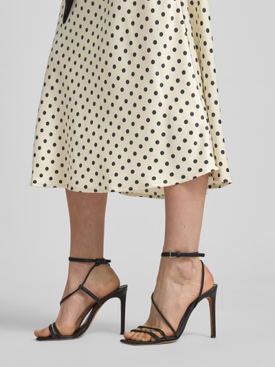 Vrouwenmodel draagt Midirock met seitlichem Reißverschluss Modell 'PELLA' van YAS in beige met zwarte stippen, straight fit, stretchmateriaal, detailopname onderlichaam.