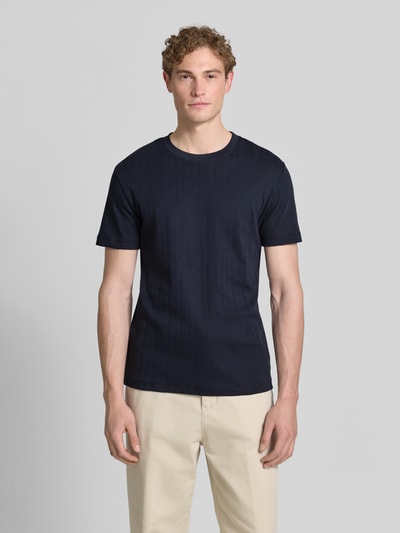 Männermodel trägt T-Shirt in Jaquard-Strick mit Rundhalsausschnitt von Lindbergh in Dunkelblau, reine Baumwolle, Regular Fit, Ganzkörperansicht von vorne.