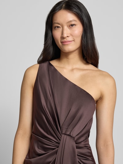 Frauenmodel trägt Abendkleid mit One-Shoulder-Träger von Adrianna Papell in Dunkelbraun, seidige Textur, Raffungen, Knotendetail, Nahaufnahme Oberkörper. Taillierte Passform, Maxilänge, Rückenlänge bei Größe 36: 135 cm, Brustweite bei Größe 36: 38 cm.