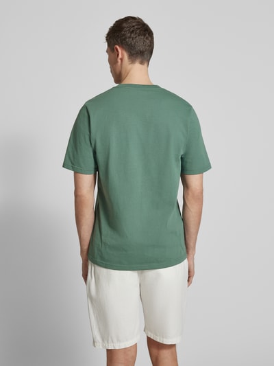 Männermodel trägt T-Shirt mit Label-Stitching Modell 'Bobby' von Wood Wood in Grün, Reine Baumwolle, Gerader Schnitt, Ganzkörperansicht Rückansicht.