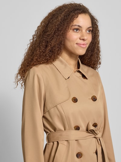 Modelka kobieca nosi Regular Fit Trenchcoat mit doppelreihiger Knopfleiste Modell 'VALERIE' od Only, beżowy, krój regular fit, pasek, długi rękaw, kieszenie boczne, widok z przodu, zbliżenie górnej części.