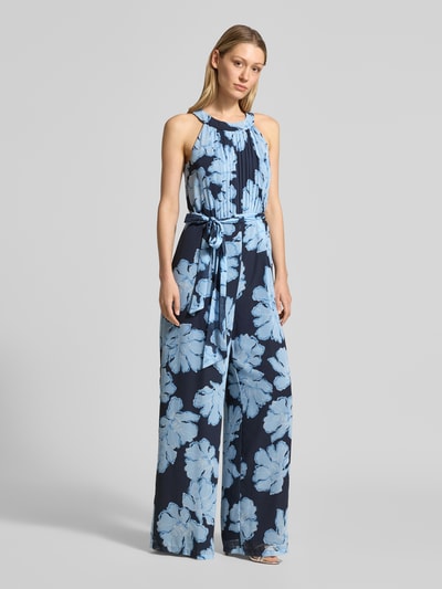Kobiece modelka nosi Jumpsuit mit Bindegürtel und Plisseefalten od Christian Berg Cocktail, niebieski, szerokie nogawki, szlachetny szyfon, krój slim fit, przód z plisami, pasek, widoczne kwiatowe wzory, widok całopostaciowy z przodu.