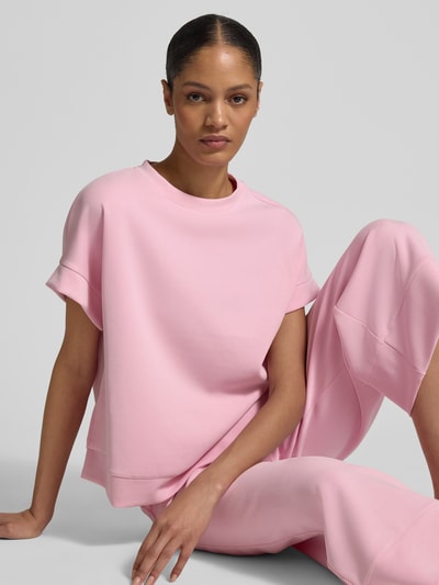Modelka kobieca ma na sobie Sweatshirt aus Modal-Mix mit Rundhalsausschnitt od Rich & Royal, różowy kolor, relaxed fit, krótki rękaw, widok całego ciała z przodu.