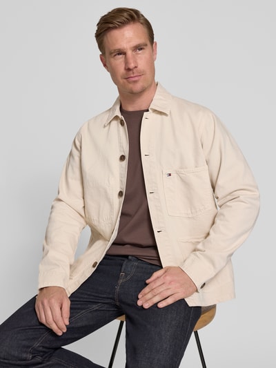 Männermodel trägt Regular Fit Hemdjacke aus reiner Baumwolle von Tommy Hilfiger, efekt: jednolity kolor, krój regular fit, wykładany kołnierz, listwa guzikowa, wyhaftowane logo, długi rękaw, mankiet, nakładana brustasza, nakładane wpuszczane kieszenie, wykończenie materiału: barwienie, rigid denim, bawełna, Ganzkörperansicht von vorne