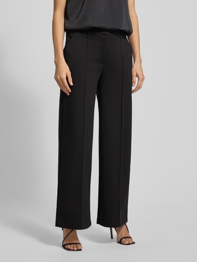 Frauenmodel trägt Wide Leg Stoffhose mit fixierten Bügelfalten Modell 'KATE' von ICHI, Material-Mix mit Viskose-Anteil, Paspeltaschen am Gesäß, schwarz, Ganzkörperansicht von vorne.