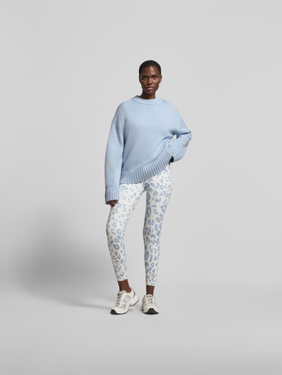 Frauenmodel trägt Leggins mit Allover-Animal-Print von Juvia in Weiß und Hellblau, Slim-Fit, breiter Bund, Knöchellänge, Ganzkörperansicht von vorne.