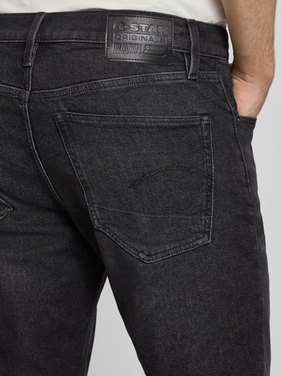Mężczyznamodel nosi Jeans mit 5-Pocket-Design von G-Star Raw, czarny bawełniano-elastanowy krój slim fit, detal tylnej kieszeni, Szerokość w rozmiarze 32/32: 41 cm, długość nogawki: 81 cm, zdjęcie z tyłu, zbliżenie górnej części.