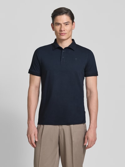 Męski model nosi Regular Fit Poloshirt mit Knopfleiste Modell 'Carlosjuan' od JOOP! Collection, bawełniany miks ze stretchem, polokołnierzyk, krótka listwa guzikowa, granatowy kolor, gładka tekstura, krój regular fit, długość pleców w rozmiarze M: 69 cm, widok całej sylwetki z przodu.