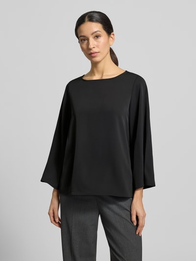 Modelka kobieca ma na sobie Blusenshirt mit Rundhalsausschnitt od comma, czarny, luźny krój, materiał z domieszką stretchu, długość tyłu 59 cm, długość rękawa 52 cm, ujęcie całej sylwetki z przodu.