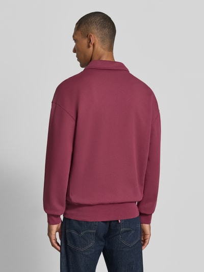 Männermodel trägt Relaxed Fit Troyer aus reiner Baumwolle Modell 'ICONIC Å GMT' von ARMEDANGELS in Weinrot, glatte Oberfläche, Ganzkörperansicht Rückansicht.