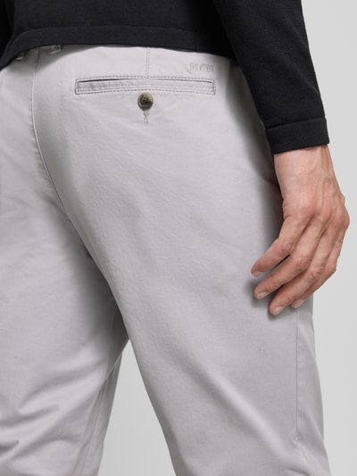 Mężczyznamodel nosi Straight Fit Hose mit Gesäßtaschen von MCNEAL z bawełny, wpuszczane kieszenie, zapięcie na guzik i zamek błyskawiczny, szerokość w rozmiarze 50: 46 cm, długość wewnętrzna nogawki: 83 cm, jasnoszary kolor, gładka tekstura, detalaufnahme z tyłu.