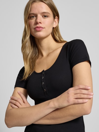Frauenmodel trägt Damen T-Shirt mit Ripp-Optik und kurzer Druckknopfleiste Modell 'KITTE' von PIECES aus Baumwoll-Elasthan-Mix, Nahaufnahme Oberkörper.