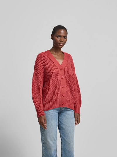 Frauenmodel trägt Oversized Wolljacke mit Kaschmir-Anteil von Joseph aus Woll-Kaschmir-Seide-Mix, Strick-Optik, gerippte Abschlüsse, durchgehende Knopfleiste, Rückenlänge 65 cm, rote Farbe, Ganzkörperansicht von vorne.