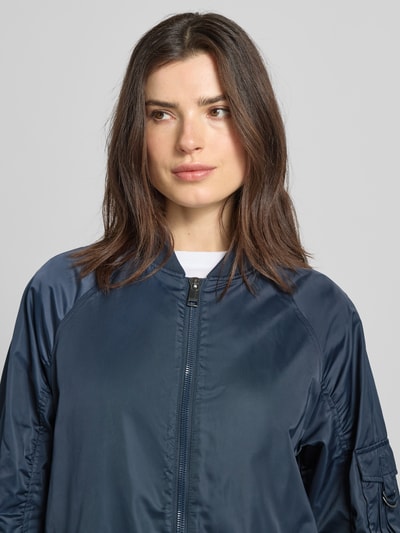 Frauenmodel trägt Regular-Fit Jacke mit Stehkragen Modell 'Ali' von Beaumont Amsterdam in Dunkelblau mit Zweiwege-Reißverschluss, Raffung, elastischen Ärmelabschlüssen und Eingrifftaschen, Nahaufnahme Oberkörper. Rückenlänge 97 cm, Schulterbreite 47 cm, Brustweite 55 cm, Ärmellänge 60 cm bei Größe 36.