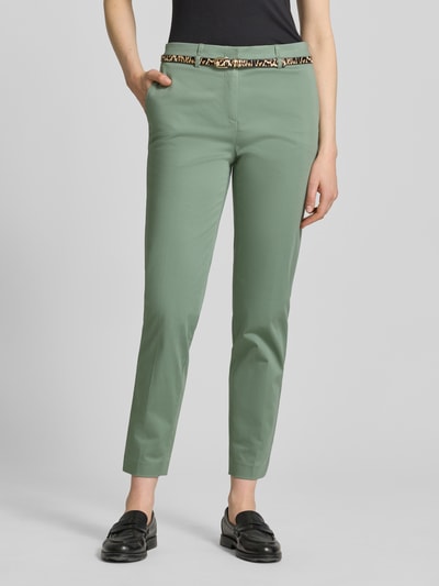 Kobiece model prezentuje Slim Fit Hose in verkürzter Passform mit Gürtel od Christian Berg Woman, mieszanka bawełny i wiskozy, krój slim fit, skrócona długość, pasek damski, szerokość w rozmiarze 36: 39 cm, długość wewnętrzna nogawki w rozmiarze 36: 72 cm, jasnozielony kolor, gładka tekstura, całopostaciowy widok z przodu.