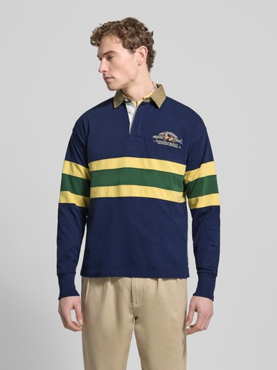 Männermodel draagt Sweatshirt mit gerippten Ärmelabschlüssen van Polo Ralph Lauren, puur katoen, regular fit, polokraag, knoopsluiting, ribboorden, labelstitching, ruglengte bij maat M 68 cm, mouwlengte bij maat M 62 cm, kleuren donkerblauw, geel en groen, Ganzkörperansicht van voren.