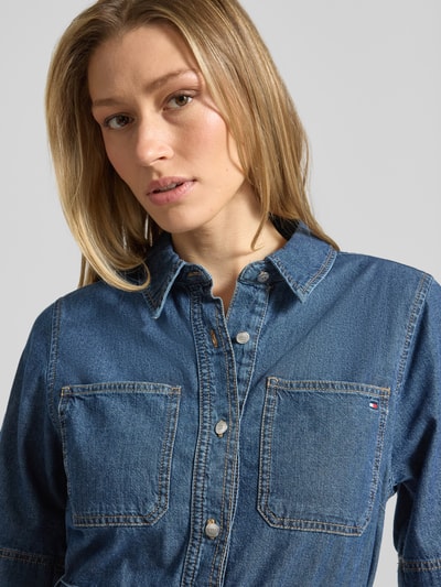 Frauenmodel trägt Fit and Flare Jeanskleid aus reiner Baumwolle von Tommy Hilfiger mit Knopfleiste, Brusttaschen, Logo-Stitching, Nahaufnahme Oberkörper.