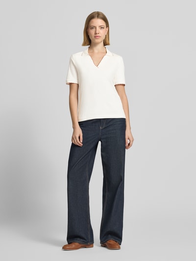 Kobiece modelka ma na sobie Slim Fit Poloshirt mit Wellensaum und V-Ausschnitt von Marc Cain, mieszanka bawełny i elastanu, krój slim fit, dekolt w serek, falisty brzeg, długość tyłu w rozmiarze 36: 58 cm, jasny kolor, gładka tekstura, całopostaciowy widok z przodu.