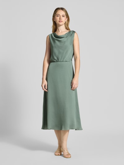 Modelka nosi Cocktailkleid in Midilänge mit Wasserfall-Ausschnitt od Swing, krój dopasowany, wzór strukturalny, podszewka nieprzezroczysta, długość midi, tylny dekolt z łezką, zamek wszyty w szew, długość pleców w rozmiarze 36: 120 cm, szerokość w rozmiarze 36: 48 cm, matowa zieleń, gładka faktura, widok całej sylwetki z przodu.