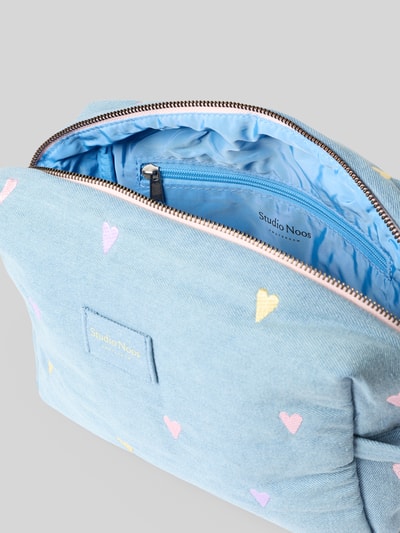 Produktfoto, Kosmetiktasche in Denim-Optik von Studio Noos mit pastellfarbenen Herz-Stickereien, Hauptfach und Innenfach mit Reißverschluss, seitliche Halteschlaufe, Baumwoll-Mix, hellblaue und rosa Farbtöne, strukturierte Textur.