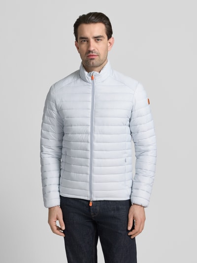 Männermodel trägt hellblaue Steppjacke mit Zweiwegereißverschluss Modell 'Alexander' von SAVE THE DUCK, Regular Fit, Ganzkörperansicht von vorne.