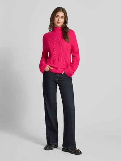 Frauenmodel trägt Strickpullover mit Stehkragen von Christian Berg Woman in Pink, lockere Passform, gerippte Abschlüsse, Ganzkörperansicht von vorne.