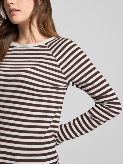 Modelka kobieca ma na sobie Slim Fit Longsleeve mit Rundhalsausschnitt Modell 'Sorka' od OPUS, czarno-białe pasy, czysta bawełna, krój slim fit, dekolt okrągły, długość tyłu w rozmiarze 36: 58 cm. Zbliżenie na górną część ciała.