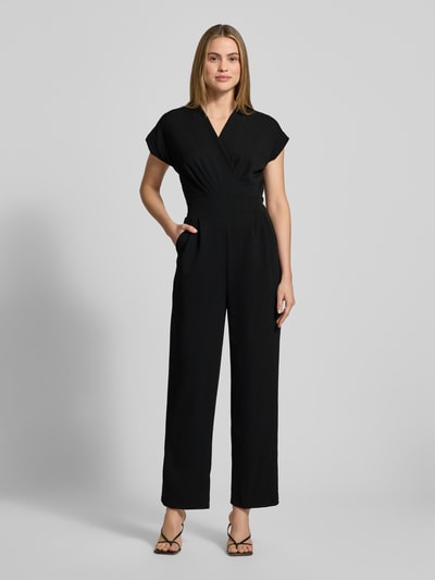 Frauenmodel trägt Jumpsuit mit Eingrifftaschen Modell 'Ko44a' von ZABAIONE in Schwarz, Material-Mix mit Stretch-Anteil, Regular-Fit, V-Ausschnitt, Ganzkörperansicht von vorne.