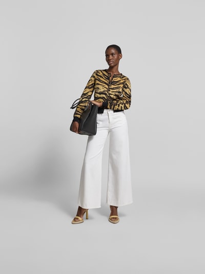 Frauenmodel trägt Strickjacke mit Viskose- und Woll-Anteil von Kenzo im Tigerprint, kombiniert mit weißer Hose, Ganzkörperansicht von vorne, Slim Fit, Rundhalsausschnitt, langärmelig, Material-Mix, durchgehende Knopfleiste, Rückenlänge Größe S 51 cm.