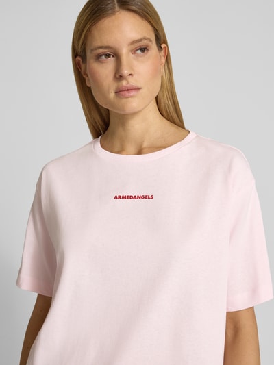Frauenmodel trägt Oversized T-Shirt aus reiner Baumwolle Modell 'GIANNAA CHAANGE' von Armedangels, unifarbenes Feinripp mit Label Print, Rundhals, Kurzarm, Nahaufnahme Oberkörper.