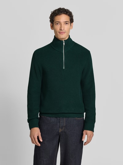 Männermodel trägt Slim Fit Strickpullover aus reiner Baumwolle mit Troyer-Kragen von MCNEAL, grün, gerippte Struktur, Ganzkörperansicht von vorne.