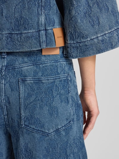 Frauenmodel trägt Barrel Fit Jeans mit 5-Pocket-Design Modell 'Rosy' von MOS MOSH in Blau mit floraler Struktur, Detailaufnahme Rückansicht, reine Baumwolle, lockerer Schnitt.