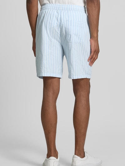 Männermodel trägt Regular Fit Shorts aus reiner Baumwolle Modell 'STUART' von SELECTED HOMME, hellblau, gestreift, Seersucker-Textur, Ganzkörperansicht Rückansicht.