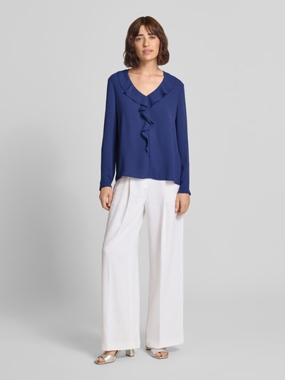 Kobiece modelki nosi Relaxed Fit Bluzę z obszyciem falbanami Marc Cain, dekolt w serek, z długim rękawem, długość tyłu w rozmiarze 36: 58 cm, długość rękawów w rozmiarze 36: 61 cm, widok całej sylwetki z przodu.