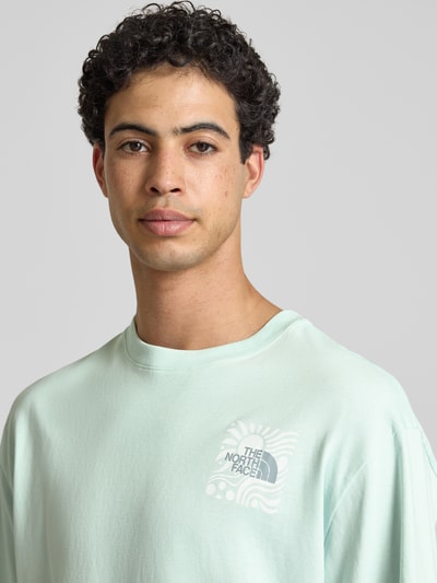 Männermodel trägt Oversized T-Shirt mit Logo-Print von The North Face aus reiner Baumwolle, Oversized-Fit, Rundhalsausschnitt, Nahaufnahme Oberkörper.