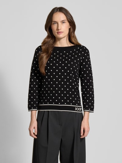 Frauenmodel trägt Strickpullover aus Viskose-Mix Modell 'Konstantina' von JOOP! mit weißen Punkten, tailliert, Nahaufnahme Oberkörper.