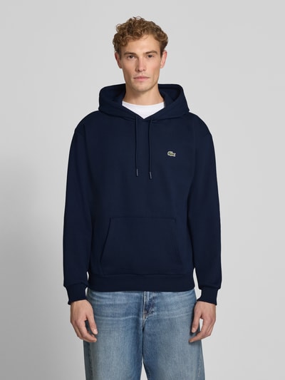 Männermodel trägt Relaxed Fit Hoodie aus katoenmix van Lacoste in donkerblauw met buidelzak, Heren sweatshirt, Ganzkörperansicht von vorne.