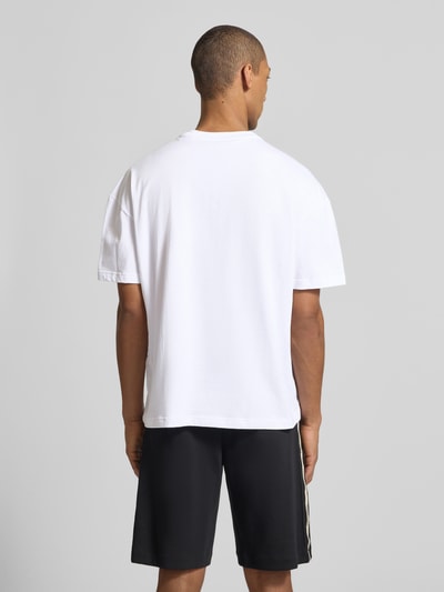 Męski model nosi T-shirt mit Logo und Rundhalsausschnitt od EA7 Emporio Armani, bawełna, krój regular fit, długość tyłu 68 cm, całkowity widok z tyłu