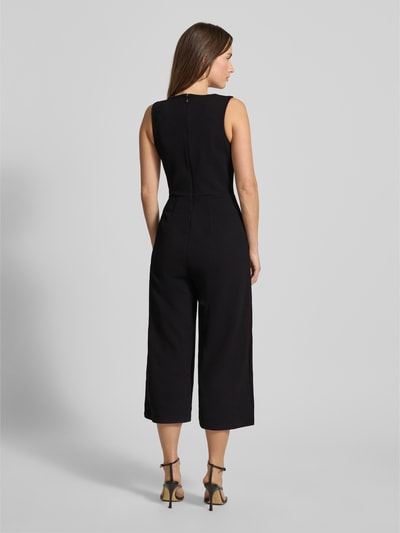 Modelka kobieca nosi czarny Jumpsuit mit Rundhalsausschnitt od Apricot, materiał z domieszką stretchu, taliowany krój, zdjęcie całej sylwetki od tyłu.
